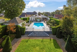 Verhoogd overzicht van een moderne tuin met zwembad en luxe villa, vastgelegd via een hoogtestatief voor een perfecte weergave van de tuinarchitectuur en het perceel.